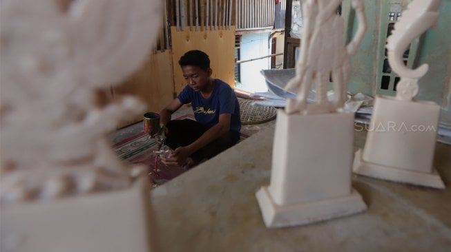 Pekerja menyelesaikan pembuatan plakat wayang dan garuda di Industri Rumahan Pluit, Penjaringan, Jakarta Utara, Rabu (30/10). [Suara.com/Angga Budhiyanto]
