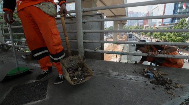 Petugas Kebersihan membersihkan jembatan penyeberangan orang (JPO) yang tidak terawat dan menimbulkan bau pesing di kawasan Karet Kuningan, Jakarta, Rabu (30/10). [Suara.com/Angga Budhiyanto]