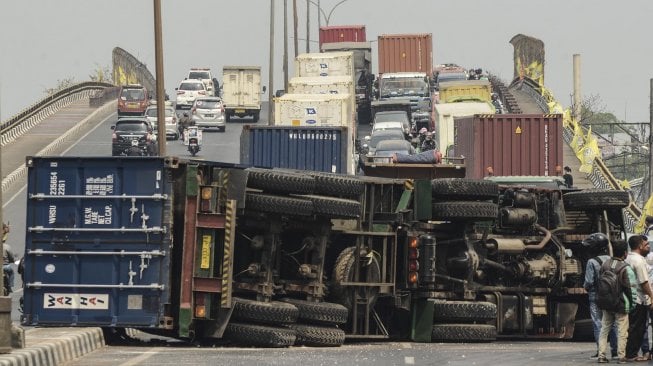 Sejumlah kendaraan melaju di sisi jalan di samping truk kontainer yang mengalami kecelakaan di Jalan Sultan Agung, daerah Kranji, Bekasi, Jawa Barat, Kamis (31/10).  [ANTARA FOTO]