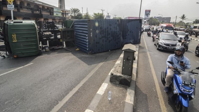 Sejumlah kendaraan melaju di sisi jalan di samping truk kontainer yang mengalami kecelakaan di Jalan Sultan Agung, daerah Kranji, Bekasi, Jawa Barat, Kamis (31/10).  [ANTARA FOTO]