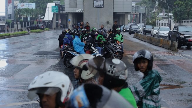 Pengendara sepeda motor mengenakan jas hujan saat melintas di Jalan Sisisingamangaraja, Kebayoran Baru, Jakarta Selatan, Jumat (1/11). [Suara.com/Angga Budhiyanto]