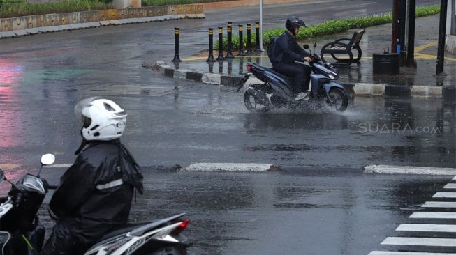 Pengendara sepeda motor mengenakan jas hujan saat melintas di Jalan Sisisingamangaraja, Kebayoran Baru, Jakarta Selatan, Jumat (1/11). [Suara.com/Angga Budhiyanto]