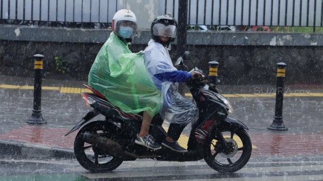 Pengendara sepeda motor mengenakan jas hujan saat melintas di Jalan Sisisingamangaraja, Kebayoran Baru, Jakarta Selatan, Jumat (1/11). [Suara.com/Angga Budhiyanto]