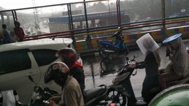 Duh, Tak Mau Basah Ada Ibu-Ibu Pakai Wadah Plastik di Kepala