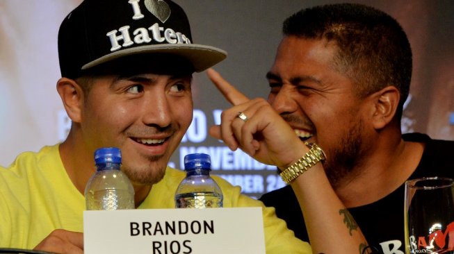 Petinju Meksiko, Brandon Rios (kiri), tertawa bersama pelatihnya Robert Garcia dalam konferensi pers jelang pertarungan melawan Manny Pacquiao di Beijing, China, Selasa (30/7/2013). [AFP/Mark Ralston]