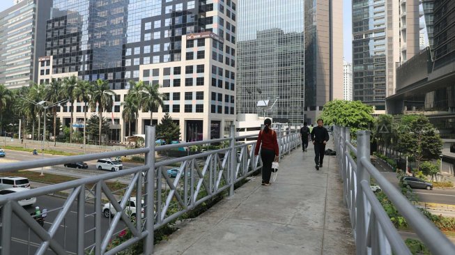 Pejalan kaki melintas di Jembatan Penyeberangan Orang (JPO) tanpa atap di Jalan Sudirman, Jakarta Pusat, Rabu (6/11). [Suara.com/Arya Manggala]