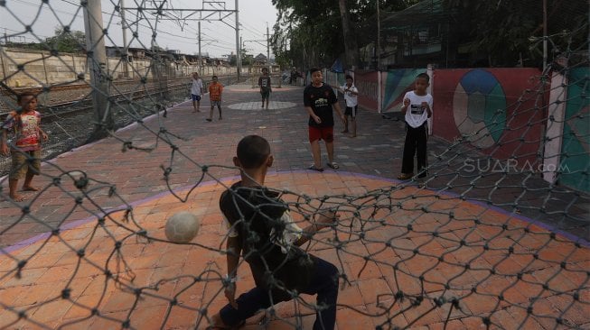 Sejumlah anak bermain sepak bola di pinggir rel kereta api di kawasan Duri, Jakarta Barat, Selasa (5/11).  [Suara.com/Angga Budhiyanto]
