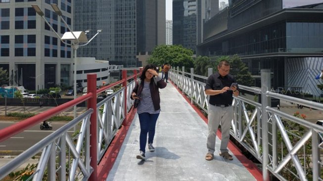 Pengguna JPO Sudirman - Thamrin, Jakarta Pusat, sebal terhadap Pemprov DKI yang mencopot atap fasilitas itu. Mereka mengatakan, lewat JPO itu saat siang hari terlampau panas. [Suara.com/Fakhri Fuadi Muflih]