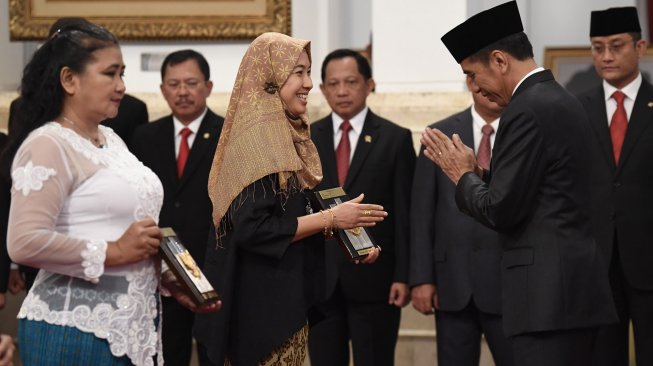 Presiden Joko Widodo (kanan) menyerahkan plakat anugerah gelar pahlawan nasional kepada ahli waris KH Masjkur di Istana Negara, Jakarta, Jumat (8/11). [ANTARA FOTO/Puspa Perwitasari]