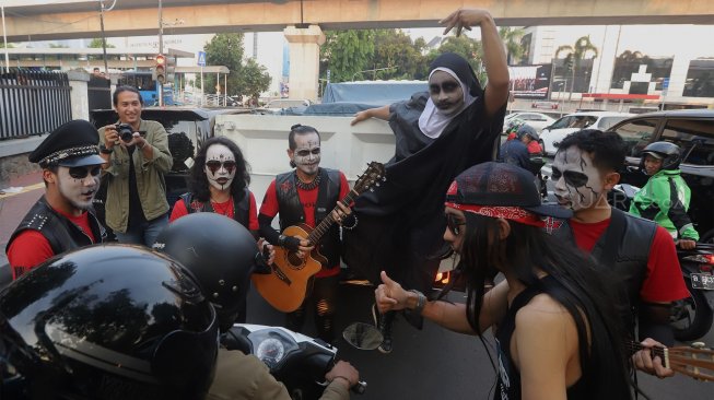 Grup musik Kuburan Band saat ngamen di Jalan Sisingamangaraja, Jakarta Selatan, Kamis (7/11). [Suara.com/Angga Budhiyanto]