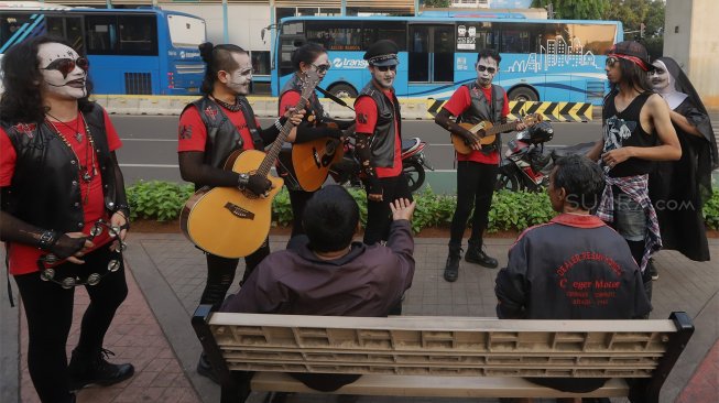 Grup musik Kuburan Band saat ngamen di Jalan Sisingamangaraja, Jakarta Selatan, Kamis (7/11). [Suara.com/Angga Budhiyanto]