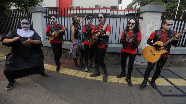 Grup musik Kuburan Band saat ngamen di Jalan Sisingamangaraja, Jakarta Selatan, Kamis (7/11). [Suara.com/Angga Budhiyanto]