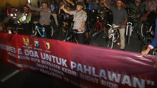 Polisi bersama sejumlah anggota komunitas pecinta sepeda 'Kediri Night Ride' melintasi rute yang telah ditentukan di Kota Kediri, Jawa Timur, Sabtu (9/11) malam. [ANTARA FOTO/Prasetia Fauzani]