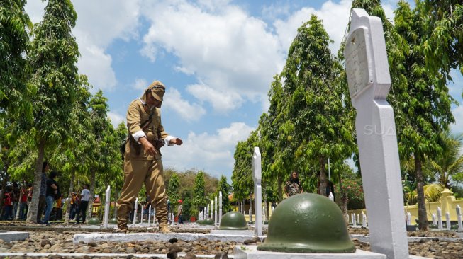 Anggota Komunitas Motor Antik Club Indonesia, Kabupaten Banyumas dengan menggunakan kostum tentara jepang menabur bunga di Makam Pahlawan Tanjung Nirwana Purwokerto, Minggu (10/11) [Suara.com/Anang Firmansyah]. 