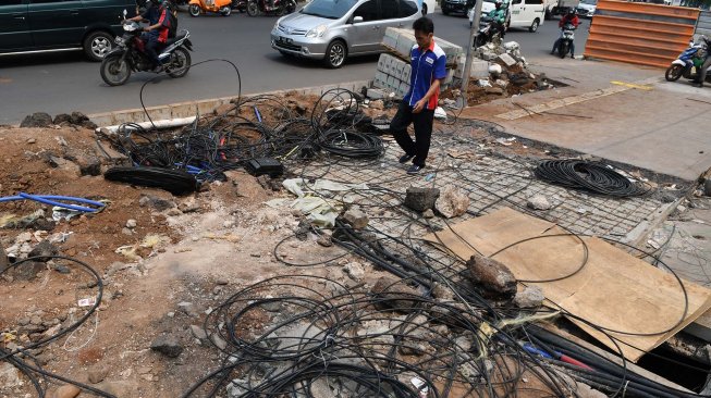 Pejalan kaki melintas di antara kabel fiber optik yang berada di jalur pedestrian, kawasan Kramat Raya, Jakarta, Senin (11/11). [ANTARA FOTO/Muhammad Adimaja]