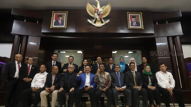 Menteri Koordinator Bidang Politik Hukum dan Keamanan Mahfud MD (tengah) didampingi Ketua Dewan Pembina Perhimpunan Advokat Indonesia Otto Hasibuan (ketiga kiri) berfoto bersama usai melakukan audiensi di Gedung Kemenko Polhukam, Jakarta, Kamis (14/11).  [Suara.com/Angga Budhiyanto]