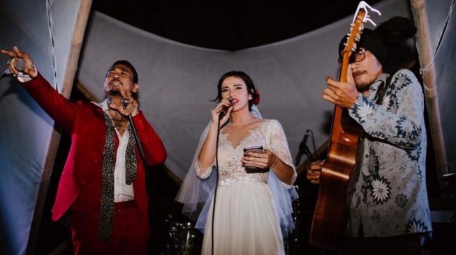 Jerinx SID dan Nora Alexandra menyanyi di acara resepsi pernikahannya sambil diiringi permainan gitar Dadang Pranoto alias Dankie. [Instagram]