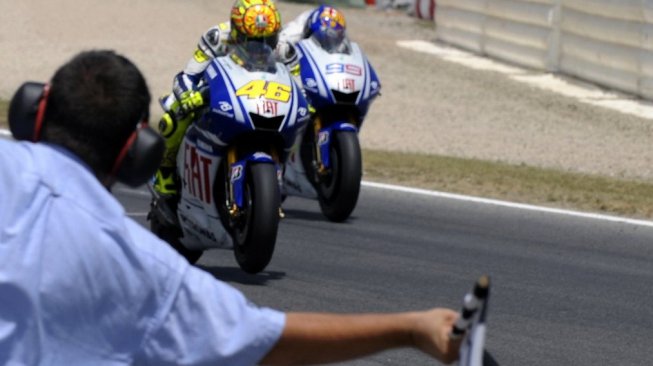 Pebalap Italia Valentino Rossi (tengah) melintasi garis finis pertama MotoGP Catalunya mengalahkan rekan satu timnya di Yamaha, Jorge Lorenzo (kiri), Minggu (14/6/2009). [AFP/Lluis Gene]