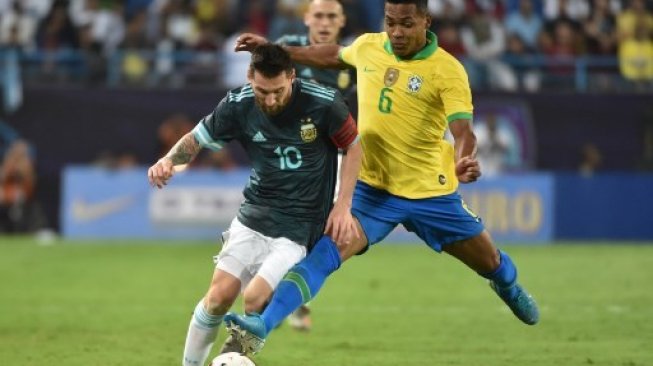 Bintang Argentina Lionel Messi ditempel ketat oleh bek Brasil Alex Sandro dalam pertandingan uji coba di King Saud University stadium, Riyadh. Fayez Nureldine / AFP