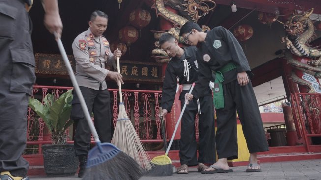 Kapolsek Tulungagung Kota Kompol Rudi Purwanto (kiri) bersama warga perguruan silat, membersihkan lantai halaman tempat ibadah (TITD) Tri Dharma di Klenteng Tjoe Tik Kiong di Tulungagung, Jawa Timur, Sabtu (16/11). [ANTARA FOTO/Destyan Sujarwoko]