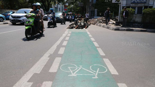 Pengguna jalan melintas di samping jalur sepeda yang dibongkar di kawasan Cikini, Jakarta, Selasa (19/11). [Suara.com/Arya Manggala]