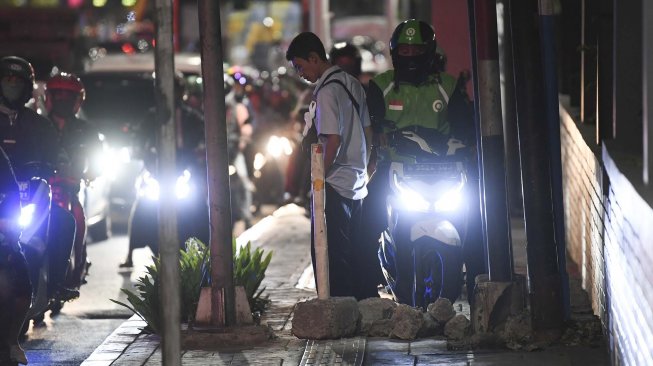 Seorang warga, Arif menghalau sepeda motor yang menaiki trotoar dengan memasang batu di Jalan Menteng Raya, Jakarta, Senin (18/11). [ANTARA FOTO/Wahyu Putro]