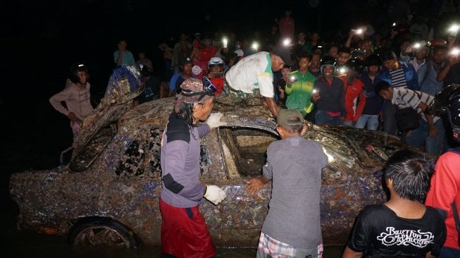 Sejumlah warga mengamati bangkai kendaraan yang diangkat dari dasar laut di Pantai Mamboro, Palu, Sulawesi Tengah, Selasa (19/11). [ANTARA FOTO/Mohamad Hamzah]