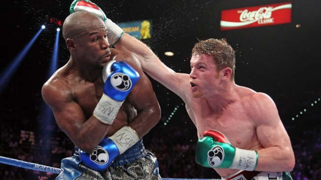 Legenda tinju dunia Floyd Mayweather Jr. (kiri) menghindar dari pukulan petinju Meksiko, Saul Alvarez, dalam duel di T-Mobile Arena, Las Vegas, AS pada, Sabtu (14/9/2013). [AFP/John Gurzinski]