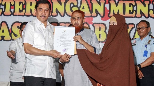 Kepala Badan Nasional Penanggulangan Terorisme (BNPT), Komjen Pol Suhardi (kiri) menyerahkan surat keputusan kepada narapidana terorisme Umar Patek (tengah) dan istrinya Gina Gutierez atau Ruqayyah binti Husein Luceno (kanan) di Lapas Kelas 1 Surabaya di Porong, Sidoarjo, Jawa Timur, Rabu (20/11). [ANTARA FOTO/Umarul Faruq]