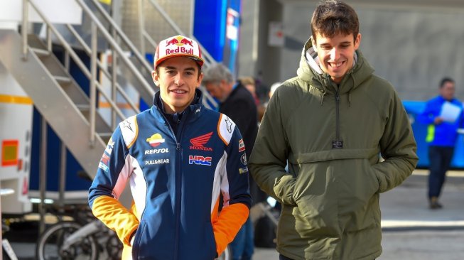 Duet pebalap Repsol Honda yang juga kakak adik, Marc Marquez (kiri) dan Alex Marquez, berjalan menuju garasi tim pada tes pramusim MotoGP 2020 di Sirkuit Ricardo Tormo, Valencia, Rabu (20/11/2019). [AFP/Jose Jordan]