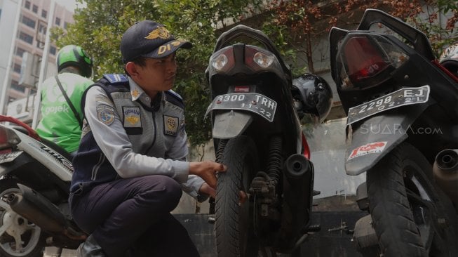 Petugas Dinas Perhubungan (Dishub) DKI Jakarta melakukan penindakan terhadap pengendara yang memarkirkan motor di trotoar di kawasan Sudirman, Jakarta, Jumat (22/11).  [Suara.com/Angga Budhiyanto]
