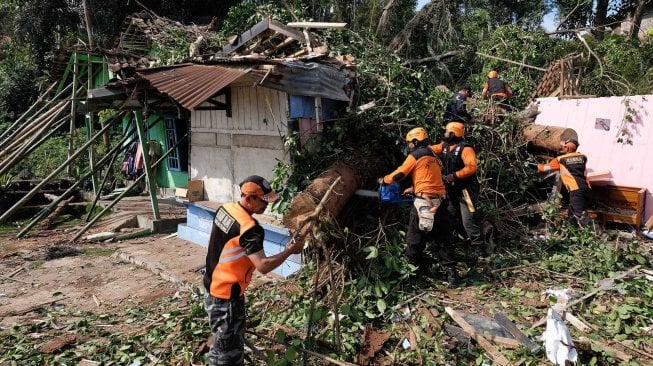 Tim SAR bersama relawan menyingkirkan batang pohon yang tumbang menimpa rumah warga di Beji, Petirejo, Ngadirejo, Temanggung, Jawa Tengah, Sabtu (23/11). [ANTARA FOTO/Anis Efizudin]