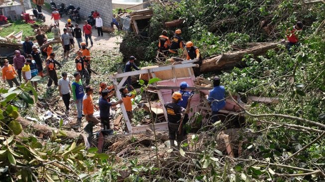 Tim SAR bersama relawan menyingkirkan batang pohon yang tumbang menimpa rumah warga di Beji, Petirejo, Ngadirejo, Temanggung, Jawa Tengah, Sabtu (23/11). [ANTARA FOTO/Anis Efizudin]