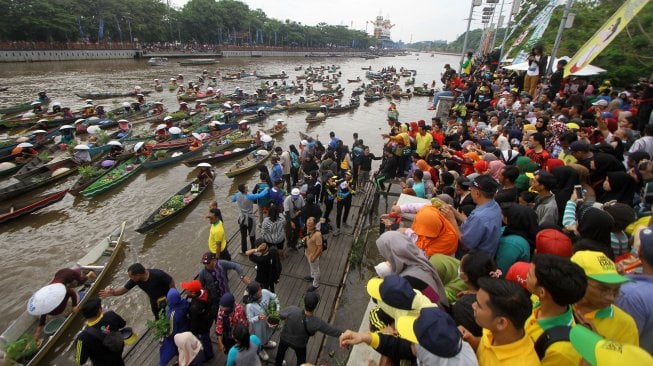 Sejumlah pedagang pasar terapung membagikan sayur dan buah di sungai Martapura, Banjarmasin, Kalimantan Selatan, Minggu (24/11). [ANTARA FOTO/Bayu Pratama S]