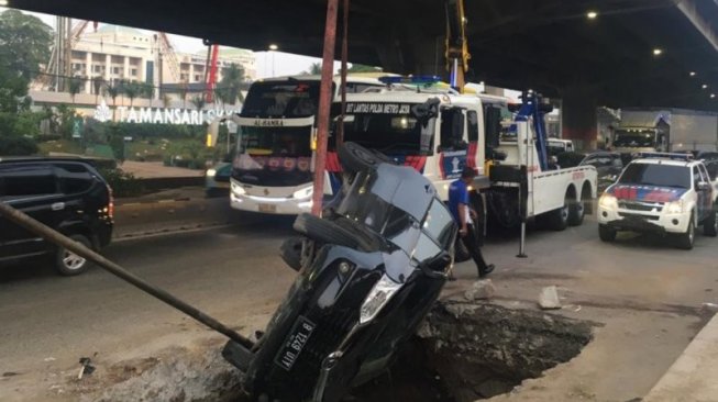 Mobil minibus terperosok lubang galian utilitas di Jalan DI Panjaitan Jakarta Timur, Senin (25/11/2019). Polisi memastikan tidak ada korban jiwa dalam kejadian itu. (ANTARA/HO-Laka Polrestro Jaktim)