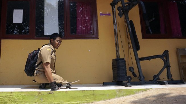 Seorang guru CPNS, Mohamat Hikmat (26), menaiki papan luncur di Sekolah Luar Biasa (SLB) Kabupaten Batang, Jawa Tengah, Senin (25/11). [ANTARA FOTO/Harviyan Perdana Putra]