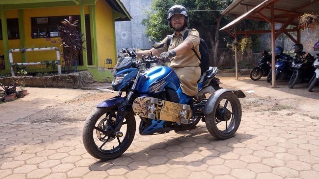 Seorang guru CPNS, Mohamat Hikmat (26), menaiki sepeda motor miliknya yang dimodifikasi di Sekolah Luar Biasa (SLB) Kabupaten Batang, Jawa Tengah, Senin (25/11).  [ANTARA FOTO/Harviyan Perdana Putra]