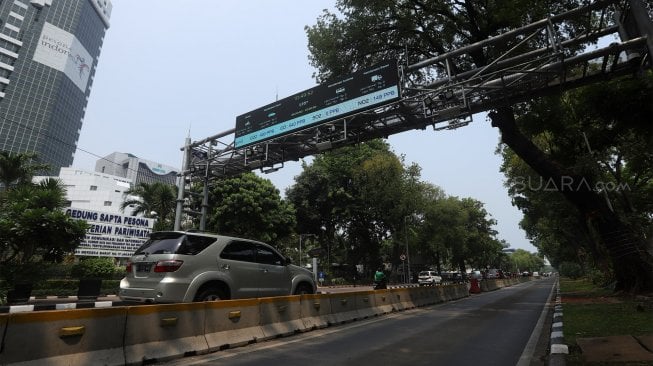 Sejumlah kendaraan melintas di bawah papan informasi Electronic Road Pricing (ERP) di Jalan Medan Merdeka Barat, Jakarta, Selasa (26/11). [Suara.com/Angga Budhiyanto]