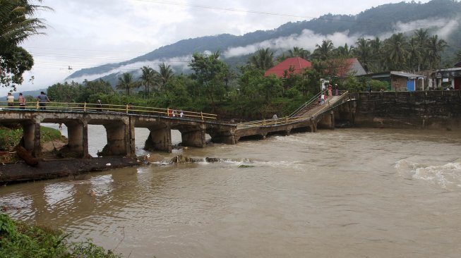 Sejumlah warga melintasi jembatan yang ambruk di Desa Sungai Pangkua, Kecamatan Koto Parik Gadang Diateh, Solok Selatan, Sumatera Barat, Selasa (26/11).[ANTARA FOTO/Muhammad Arif Pribadi]