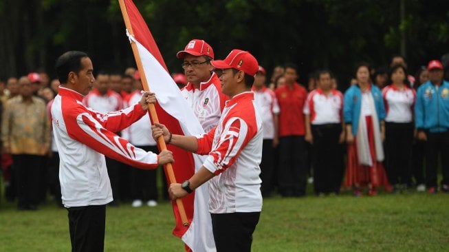 Presiden Joko Widodo (kiri) menyerahkan bendera kepada Ketua Komite Olimpiade Indonesia (KOI) Raja Sapta Oktohari (kanan) disaksikan Ketua Kontingen Indonesia Harry Warganegara (tengah) saat pelepasan atlet untuk SEA Games 2019 di Istana Bogor, Jawa Barat, Rabu (27/11). [ANTARA FOTO/Akbar Nugroho Gumay]
