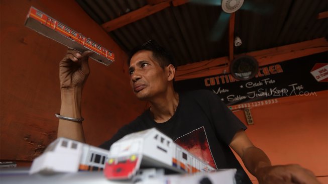 Iskandar (52) menyelesaikan pembuatan miniatur kereta api di kawasan Manggarai, Jakarta, Rabu (27/11).[Suara.com/Angga Budhiyanto]