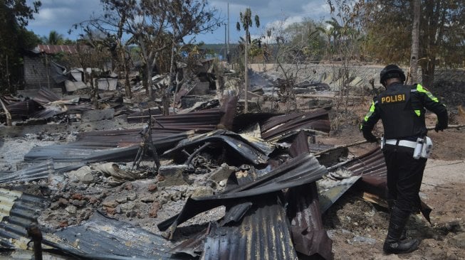 Personel dari Polres Buton berada di tengah puing-puing rumah yang dibakar oleh keributan antar warga di Desa Wadiabero, Kecamatan GU, Kabupaten Buton Tengah, Sulawesi Tenggara, Kamis (28/11). [ANTARA FOTO / Rj / Jojon]