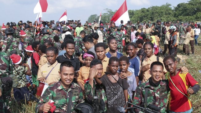 Prajurit TNI berpose dengan warga seusai melakukan terjun statis saat kunjungan Panglima TNI Marsekal TNI Hadi Tjahjanto beserta rombongan di Timika, Papua, Jumat (29/11). [ANTARA FOTO/Sevianto Pakiding]