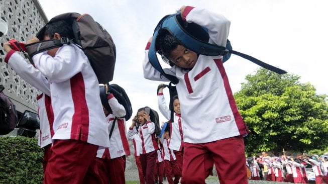 
Pelajar melindungi kepala dengan tas saat mengikuti kompetisi simulasi evakuasi mandiri bencana gempa dan tsunami di Museum Tsunami, Banda Aceh, Aceh, Jumat (29/11). [ANTARA FOTO/Irwansyah Putra]