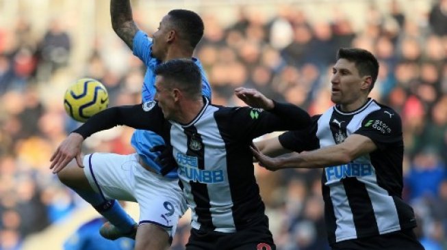 Pemain Manchester City Gabriel Jesus berebut bola dengan dua pemain Newcastle United dalam laga Liga Inggris di St James' Park, Sabtu (30/11/2019). [AFP]