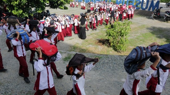 
Pelajar melindungi kepala dengan tas saat mengikuti kompetisi simulasi evakuasi mandiri bencana gempa dan tsunami di Museum Tsunami, Banda Aceh, Aceh, Jumat (29/11). [ANTARA FOTO/Irwansyah Putra]