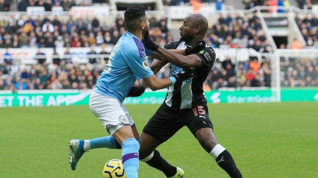 Bek Newcastle United Ciaran Clark bersaing dengan bek Manchester City John Stones saat pertandingan sepak bola Liga Inggris antara Newcastle melawan Manchester City di St James 'Park, Newcastle-upon-Tyne, Inggris, Sabtu (30/11). [Lindsey Parnaby / AFP]