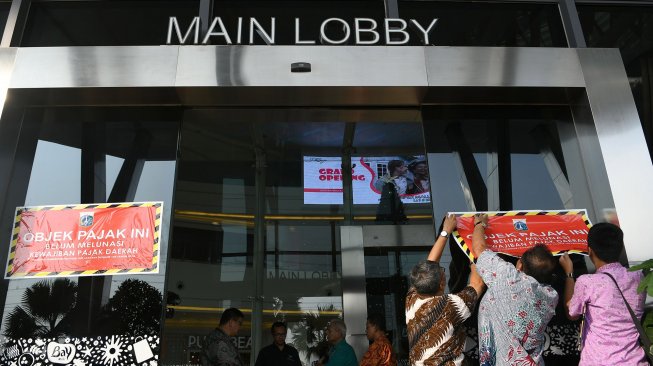 Petugas Badan Pajak dan Restribusi Daerah (BPRD) DKI Jakarta menempelkan stiker 'Objek Pajak' saat Supervisi pencegahan pajak di Mall Baywalk, Pluit, Jakarta Utara di Jakarta, Kamis (5/12). [ANTARA FOTO/M Risyal Hidayat]