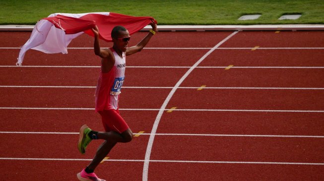 Pelari Indonesia Agus Prayogo mengibarkan bendera Merah Putih saat memasuki garis finish nomor marathon putra SEA Games 2019 di Stadion Atletik New Clark City, Clark, Filipina, Jumat (6/12). [ANTARA FOTO/Aditya ES Wicaksono]