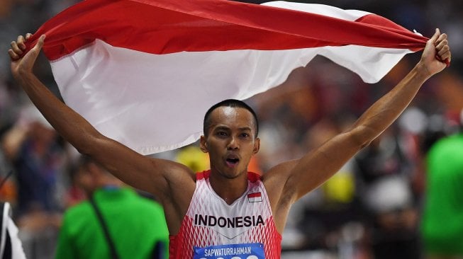 Atlet lompat jauh Indonesia Sapwaturrahman mengibarkan Bendera Merah Putih setelah berhasil memenangkan pertandingan Lompat Jauh Putra SEA Games ke-30 di Stadion Atletik New Clark, Filipina, Sabtu (7/12). [ANTARA FOTO/Nyoman Budhiana]